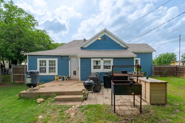 back of house featuring a lawn, a fenced backyard, a shingled roof, and a patio area