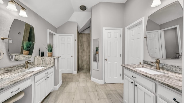 bathroom featuring two vanities, lofted ceiling, and a sink