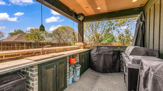 view of patio featuring grilling area, a fenced backyard, and an outdoor kitchen