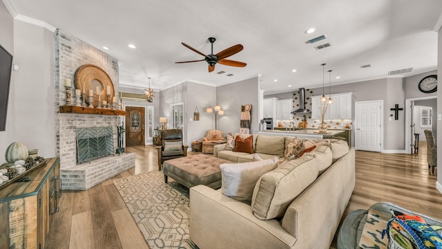 living room featuring recessed lighting, a brick fireplace, ceiling fan, visible vents, and light wood-style flooring