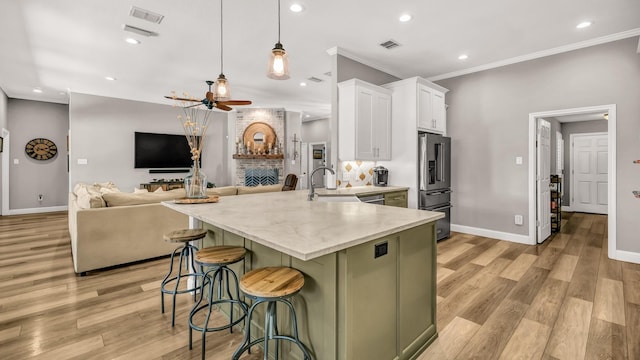 kitchen featuring a breakfast bar area, white cabinets, visible vents, high end refrigerator, and a ceiling fan