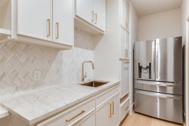 6814 Glendora Ave, Dallas, TX 75230 - kitchen with stainless steel fridge with ice dispenser, a sink, backsplash, light stone counters, and white cabinetry