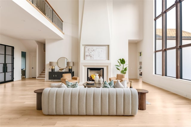 6814 Glendora Ave, Dallas, TX 75230 - living area featuring a towering ceiling, stairway, light wood-style floors, a lit fireplace, and baseboards