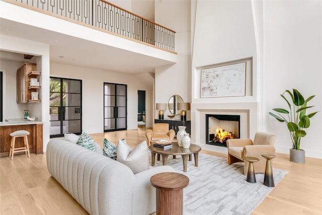 6814 Glendora Ave, Dallas, TX 75230 - living room featuring light wood finished floors, a towering ceiling, and a lit fireplace