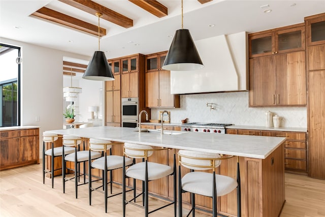 6814 Glendora Ave, Dallas, TX 75230 - kitchen featuring a sink, beamed ceiling, light wood finished floors, tasteful backsplash, and a large island