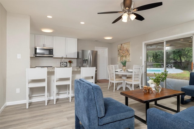 living area featuring recessed lighting, baseboards, a ceiling fan, and light wood finished floors