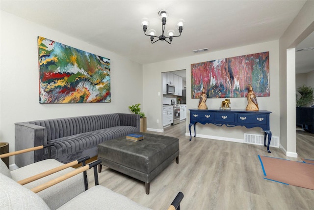 living area featuring an inviting chandelier, baseboards, light wood finished floors, and visible vents