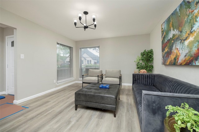 living area with baseboards, an inviting chandelier, and wood finished floors