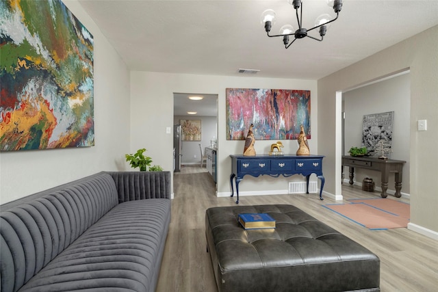 living area with baseboards, a notable chandelier, visible vents, and wood finished floors