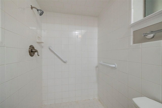 bathroom featuring a tile shower and toilet