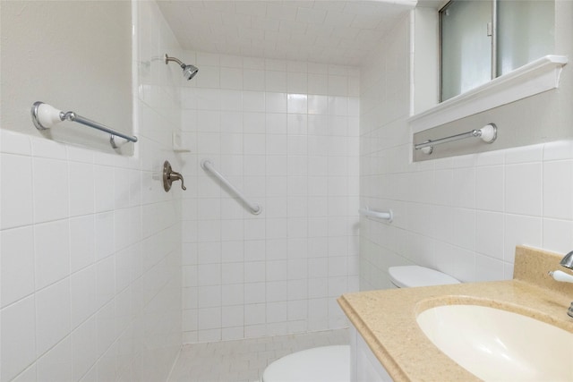 bathroom with vanity, tile walls, a tile shower, and toilet