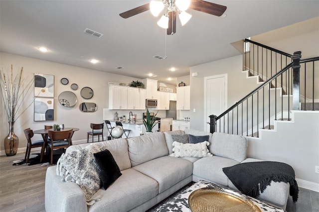 6246 Rilla St, Frisco, TX 75035 - living room with visible vents, light wood finished floors, baseboards, stairway, and a ceiling fan