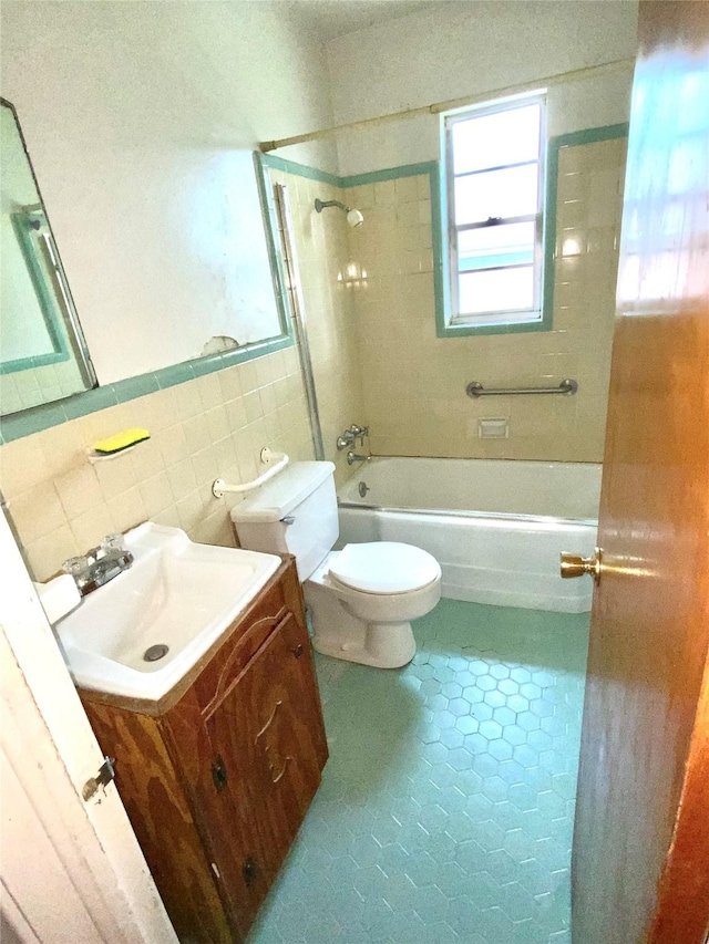 bathroom with shower / bathtub combination, toilet, tile walls, tile patterned floors, and vanity