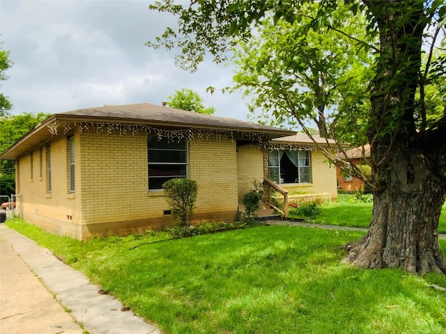 view of front facade with a front yard, crawl space, and brick siding