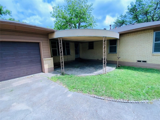 view of front of home featuring driveway, a carport, a front yard, an attached garage, and brick siding