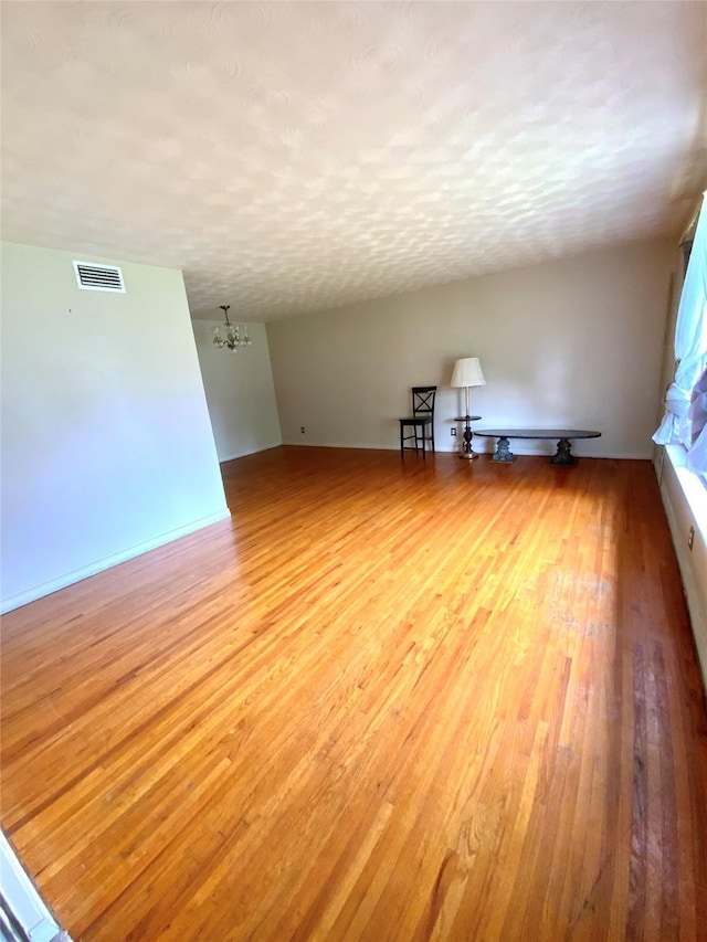 spare room featuring a chandelier, visible vents, and wood-type flooring