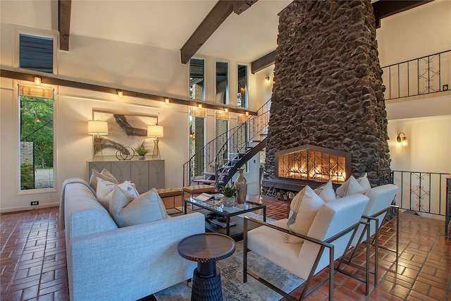 living room featuring beam ceiling, a high ceiling, stairway, baseboards, and brick floor