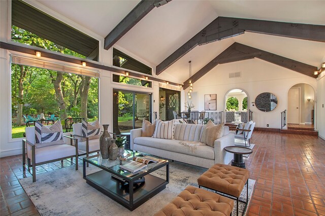 living room with baseboards, arched walkways, brick floor, and high vaulted ceiling