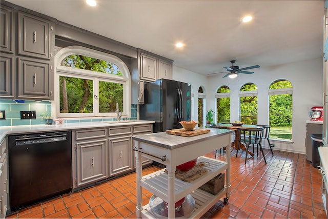 kitchen featuring light countertops, gray cabinetry, a wealth of natural light, and black appliances