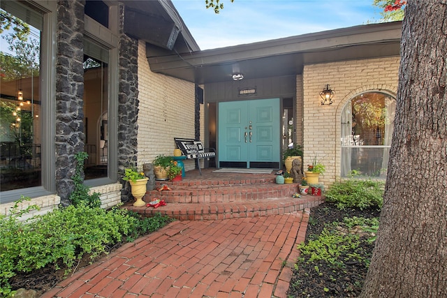 view of exterior entry with covered porch and brick siding