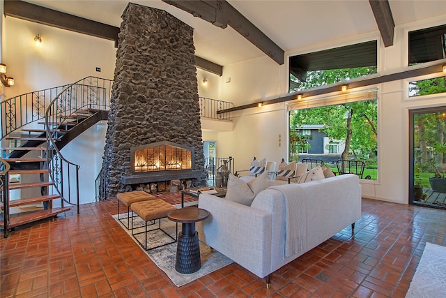living area featuring a towering ceiling, beam ceiling, stairway, and brick floor