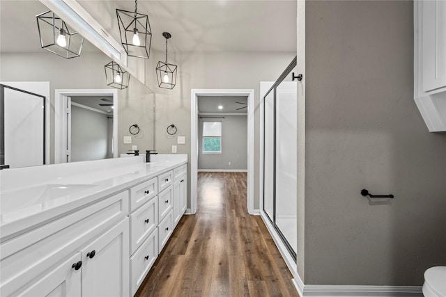 bathroom featuring double vanity, a sink, a shower stall, and wood finished floors