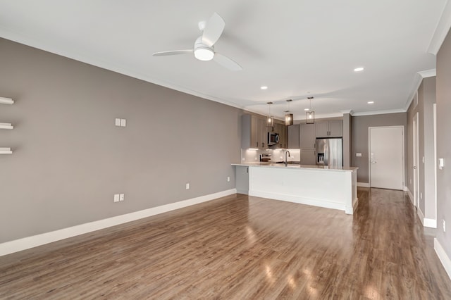 unfurnished living room with wood finished floors, ceiling fan, crown molding, and baseboards