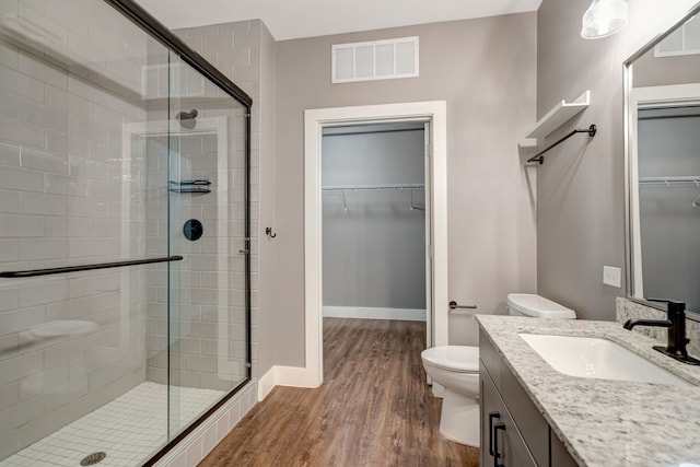 full bath featuring a shower stall, vanity, toilet, visible vents, and wood finished floors