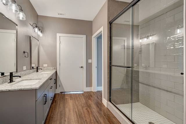 full bathroom with a sink, visible vents, a shower stall, and wood finished floors