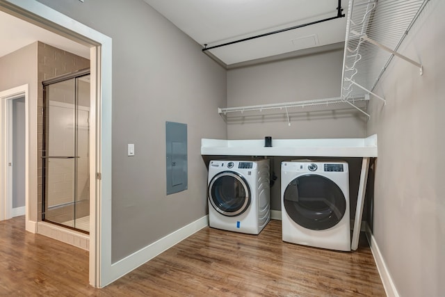 washroom with wood finished floors, washer and clothes dryer, electric panel, and laundry area