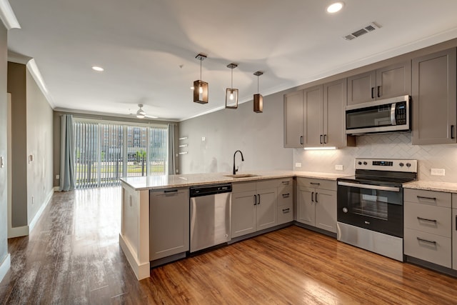 kitchen with gray cabinetry, stainless steel appliances, ornamental molding, and a sink