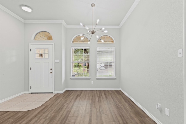 foyer with baseboards, ornamental molding, wood finished floors, and a notable chandelier