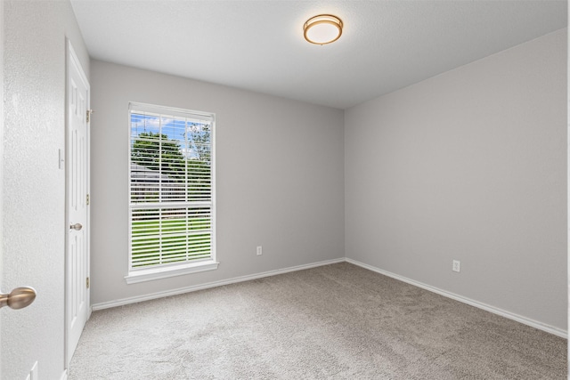 carpeted empty room featuring baseboards