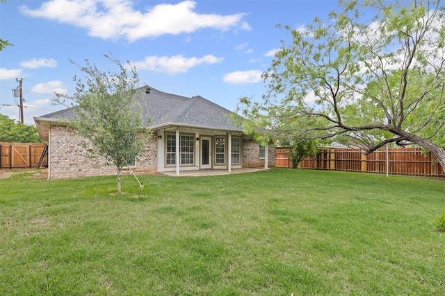rear view of property with brick siding, a fenced backyard, a patio area, and a yard