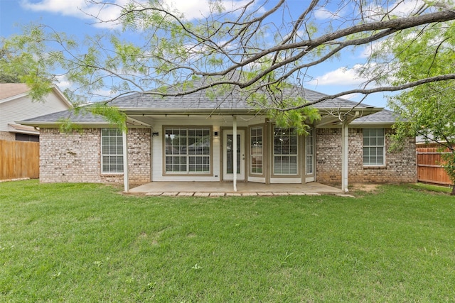 rear view of house with a yard, brick siding, fence, and a patio