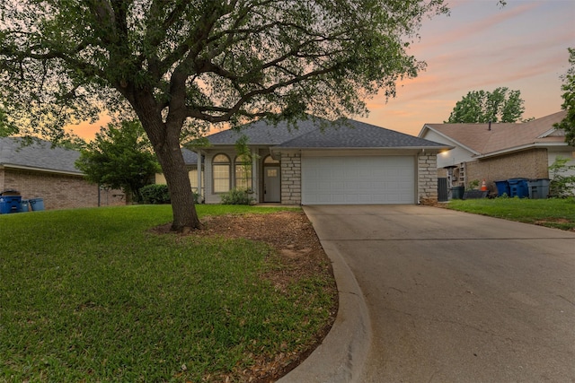 ranch-style house featuring an attached garage, a front yard, driveway, and stone siding