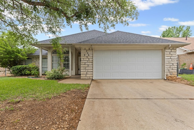 ranch-style house with roof with shingles, an attached garage, brick siding, a front yard, and driveway