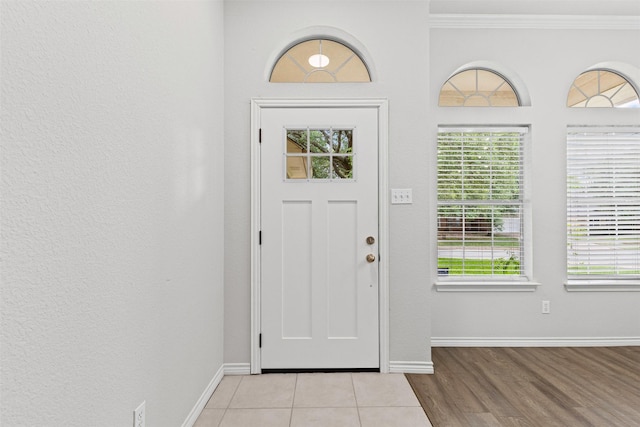 foyer entrance featuring baseboards, ornamental molding, and wood finished floors