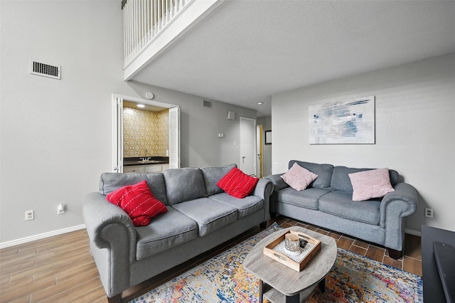 living room featuring wood tiled floor, visible vents, and baseboards
