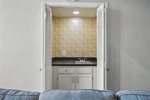 bathroom featuring wallpapered walls and a sink