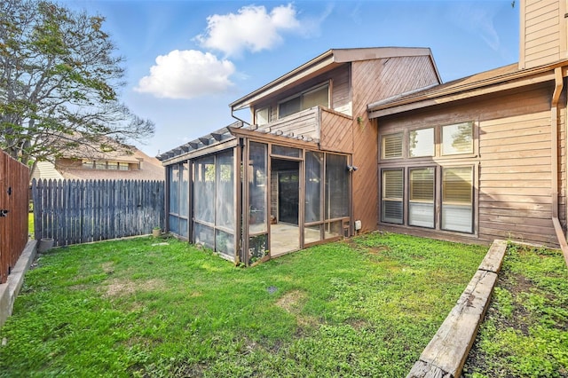 back of property with a sunroom, a yard, and a fenced backyard