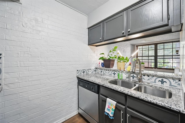 kitchen featuring dark wood finished floors, light stone countertops, stainless steel dishwasher, and a sink
