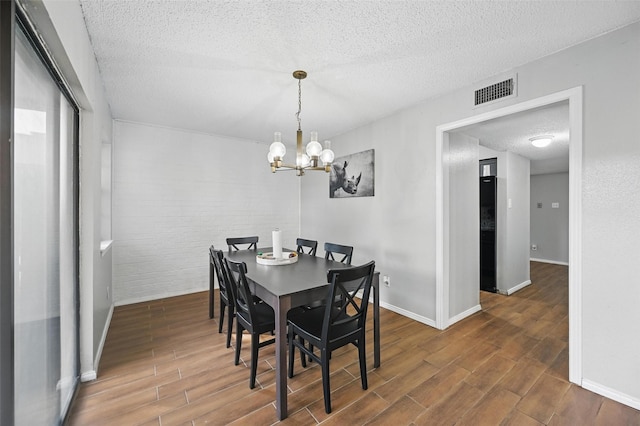 dining room featuring baseboards, visible vents, wood finished floors, and a textured ceiling