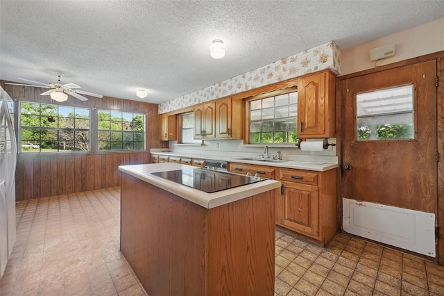 kitchen with a sink, wood walls, light countertops, a textured ceiling, and plenty of natural light