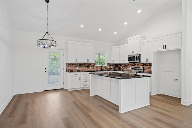 kitchen featuring dark countertops, appliances with stainless steel finishes, light wood-style flooring, and decorative backsplash