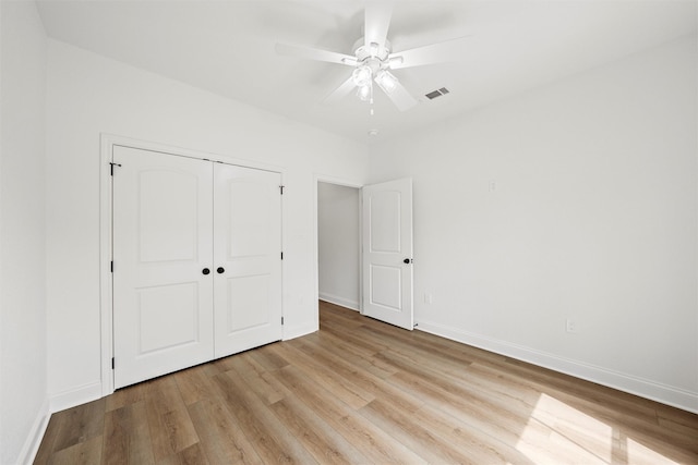 unfurnished bedroom with a closet, visible vents, wood finished floors, and baseboards