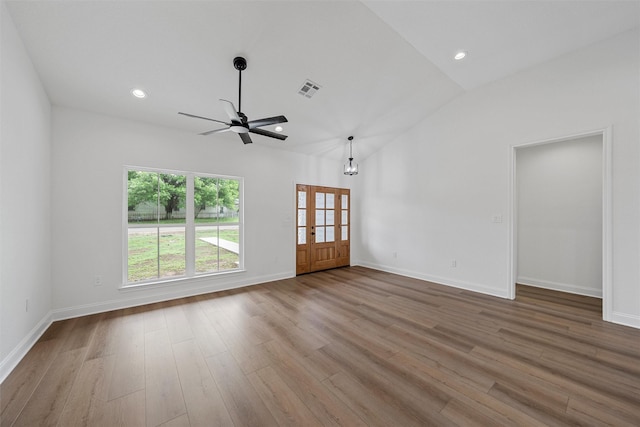 unfurnished living room with ceiling fan, visible vents, baseboards, vaulted ceiling, and wood finished floors