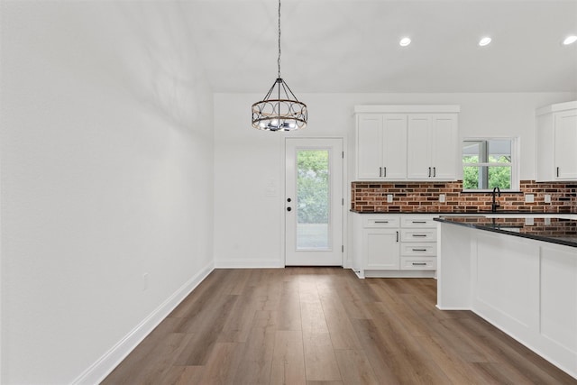 kitchen featuring white cabinetry, an inviting chandelier, recessed lighting, wood finished floors, and backsplash