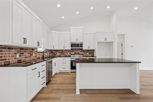 kitchen with stainless steel appliances, decorative backsplash, white cabinets, and a kitchen island