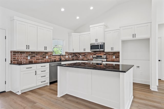 kitchen with appliances with stainless steel finishes, a center island, light wood-style flooring, and backsplash